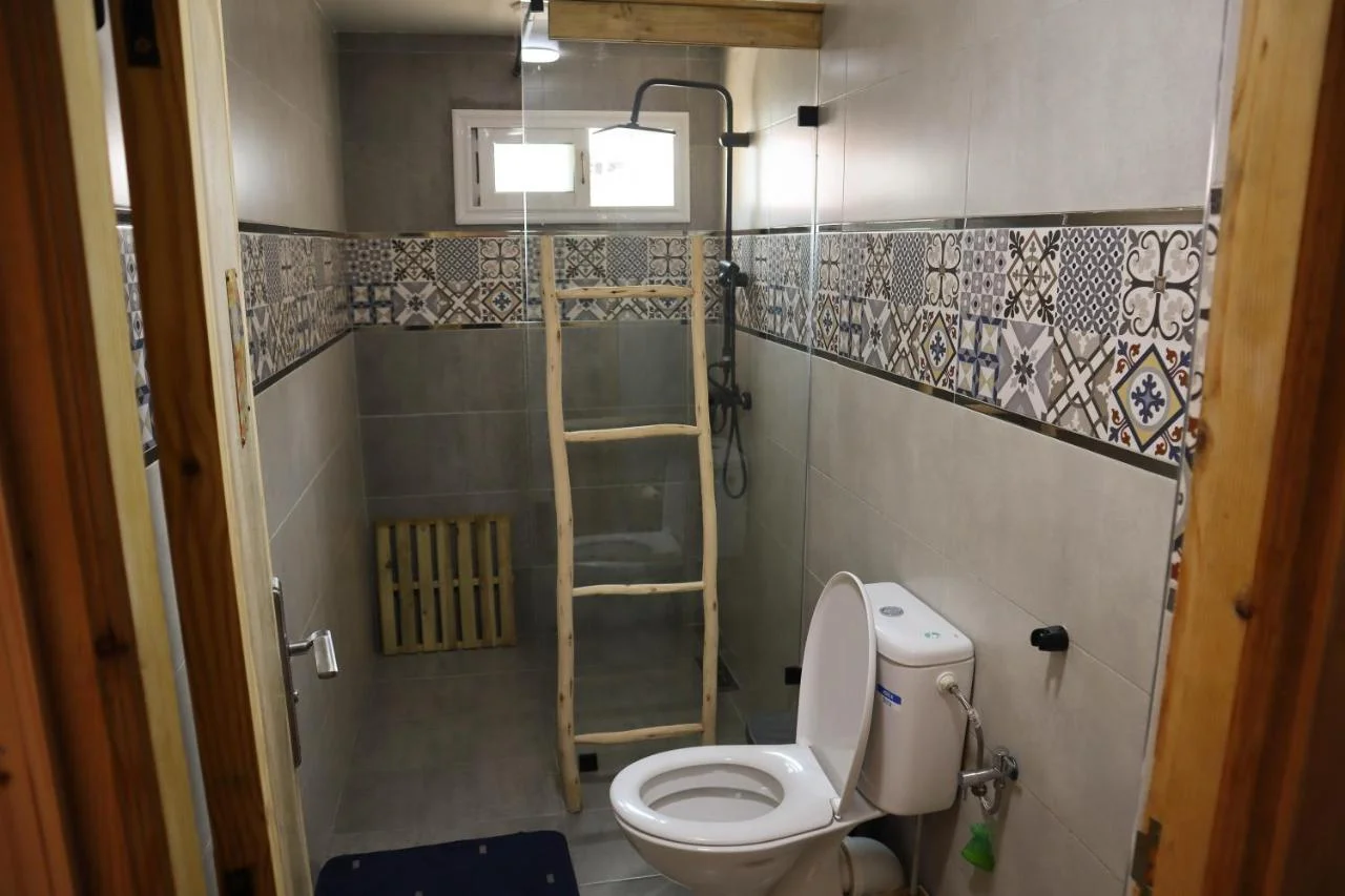 Bathroom at Grip Sea Morocco in Anza with patterned tile, a glass shower screen and toilet