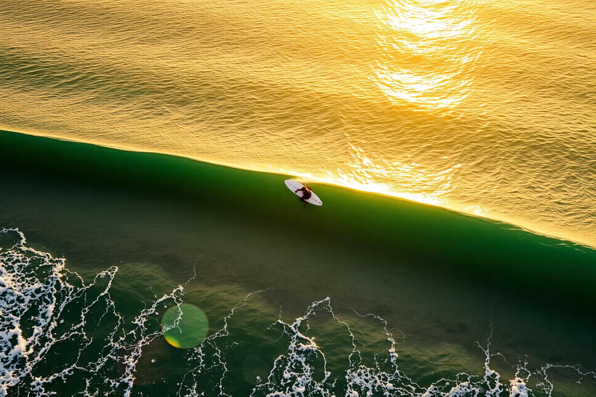 Aerial view of a surfer on a glassy Atlantic wave near Taghazout at golden hour