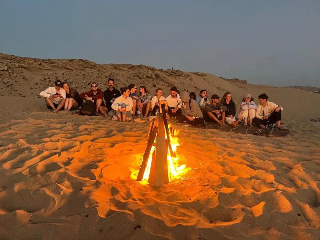 Jamal and the camp crew gathered around an evening beach fire after a Taghazout surf session