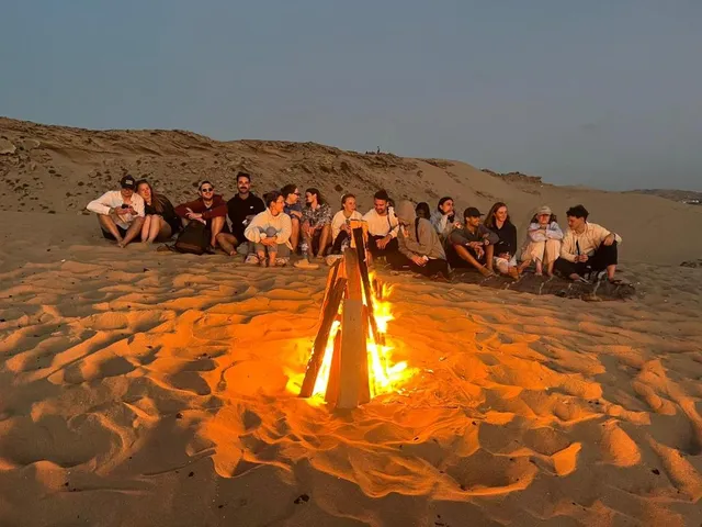 A group gathered around a beach fire