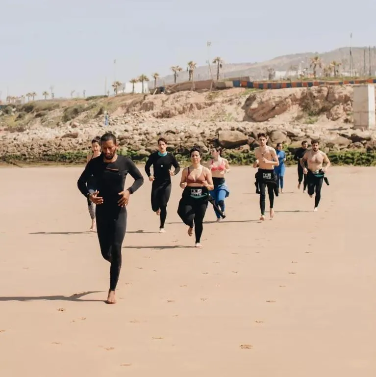 Jamal leading a warm-up routine with surf students before a Taghazout Bay session