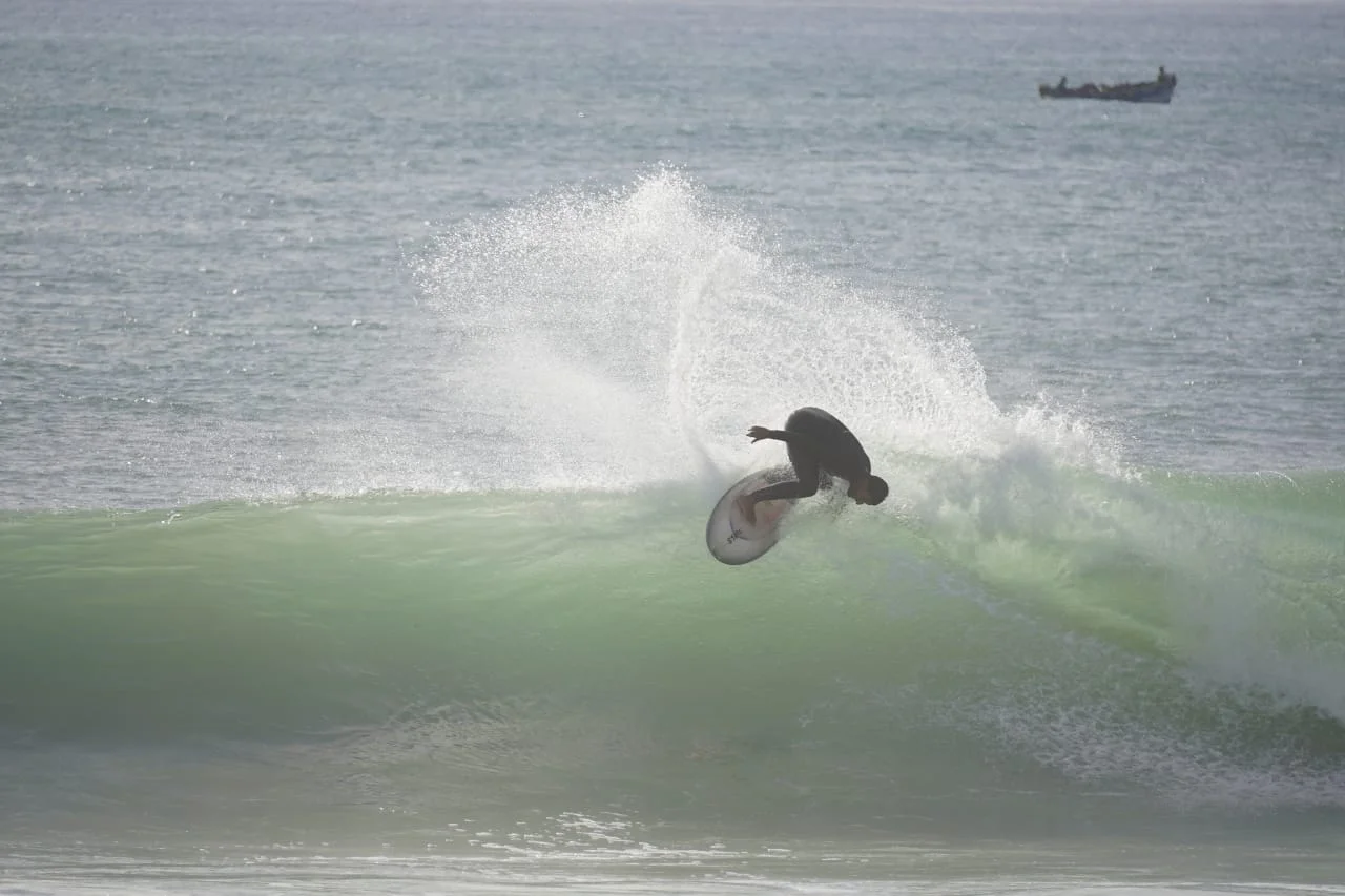 Jamal riding across a breaking wave on his surfboard